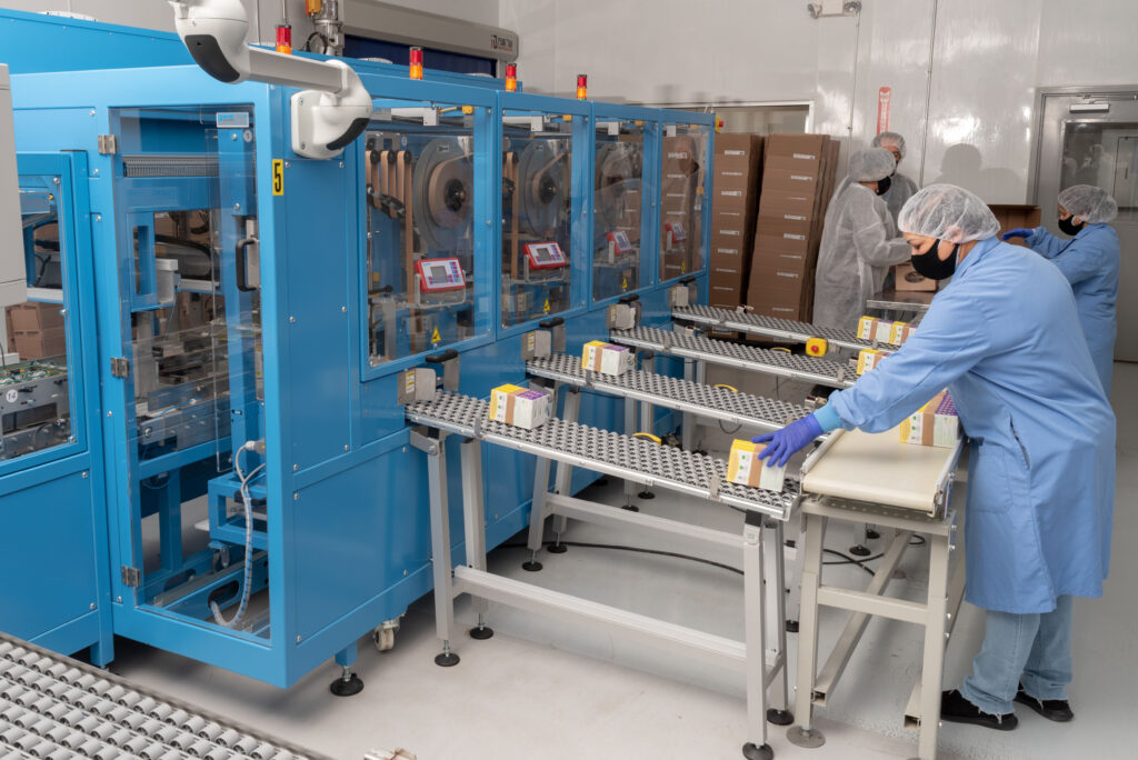 Technician overseeing automated packaging equipment in a Vitaquest facility