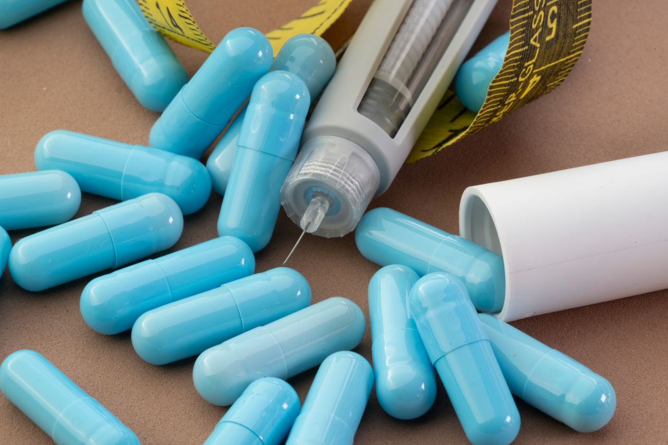 Blue capsules surrounding a GLP-1 injection pen, representing GLP-1 support supplements for healthy weight management, blood sugar support, and nutritional wellness. Blue capsules surrounding a GLP-1 injection pen, representing GLP-1 support supplements for healthy weight management, blood sugar support, and nutritional wellness.