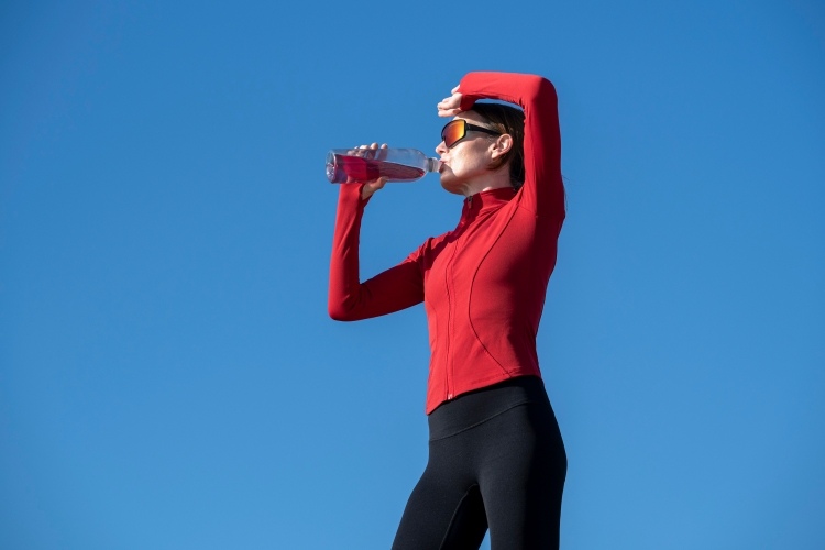 Hydration supplement flavor trends illustrated by a woman taking a hydration break outdoors.