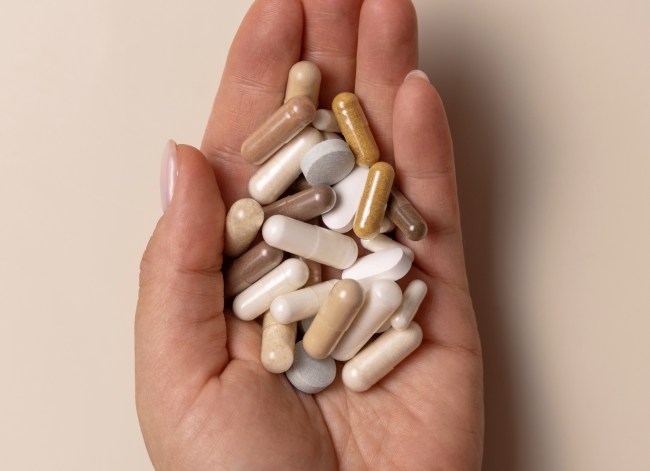 Assorted supplement capsules and tablets in a palm, illustrating dietary fiber supplement formats.
